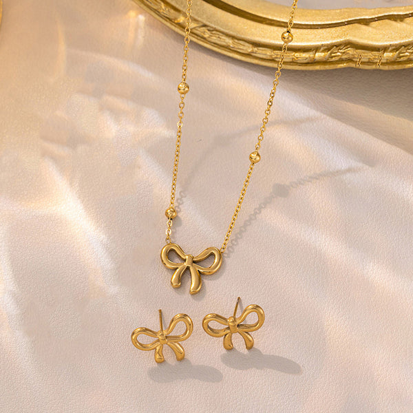 Sweet Bow Muse Duo – Anti-tarnish 18k Gold-plated Bow Chain Pendant & Bow Ear Studs on a soft pink background