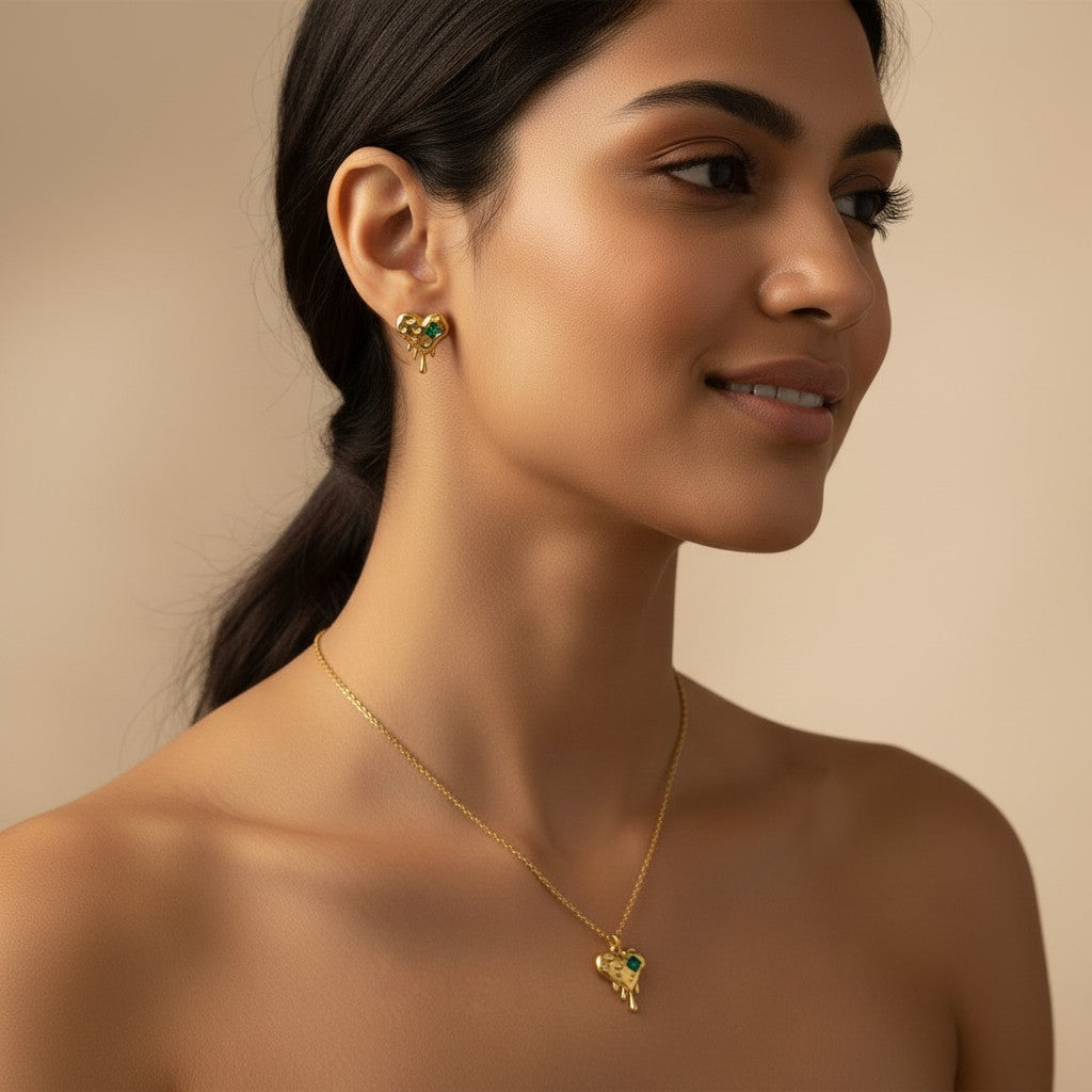 Woman wearing K-Glow Emerald Heart Drip Gold-Plated Anti-Tarnish Jewellery Set for Women - Melted Heart Necklace & Earrings against a beige background