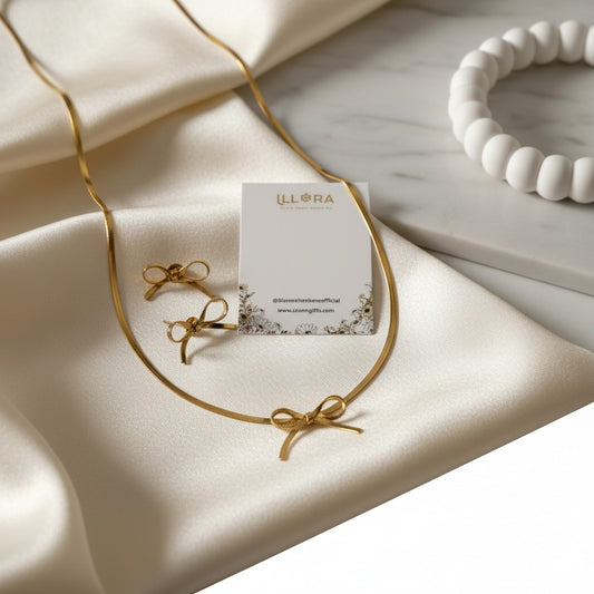 K-Glow Ribbon Duo Gold Plated Anti-Tarnish Jewellery Set for Women - Bow Necklace & Earrings on a beige fabric background