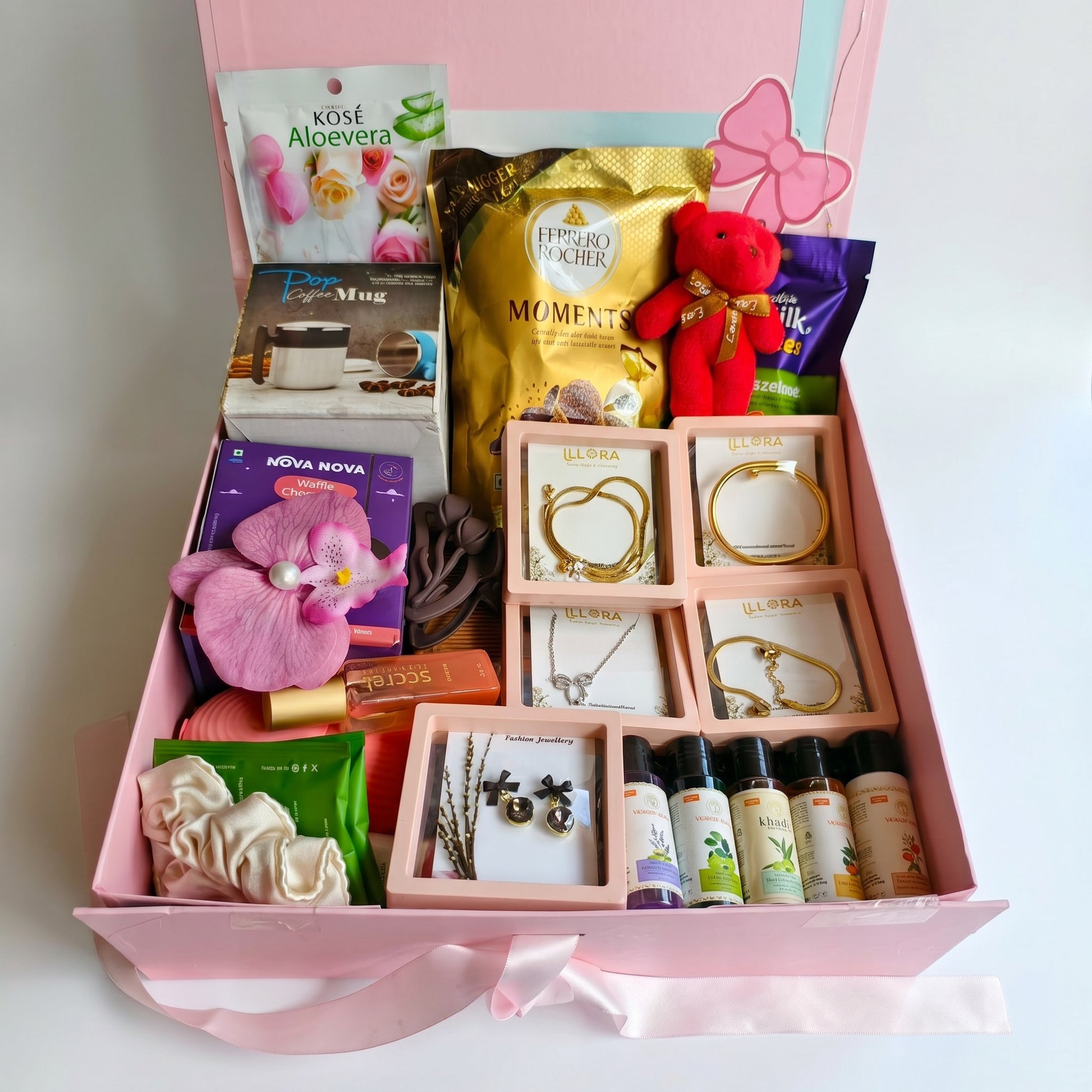 Gift Hamper For Women and girls with travel care products, accessories, teddy key chain, sweet treats, and jewellery on a white background