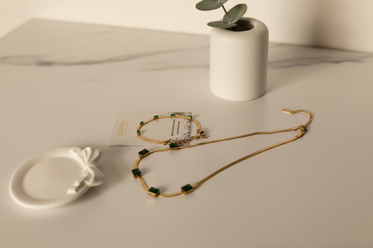 Gold-plated Green Emerald Stone Embedded Snake Necklace & Snake Bracelet Set on a light surface with a small plant in the background