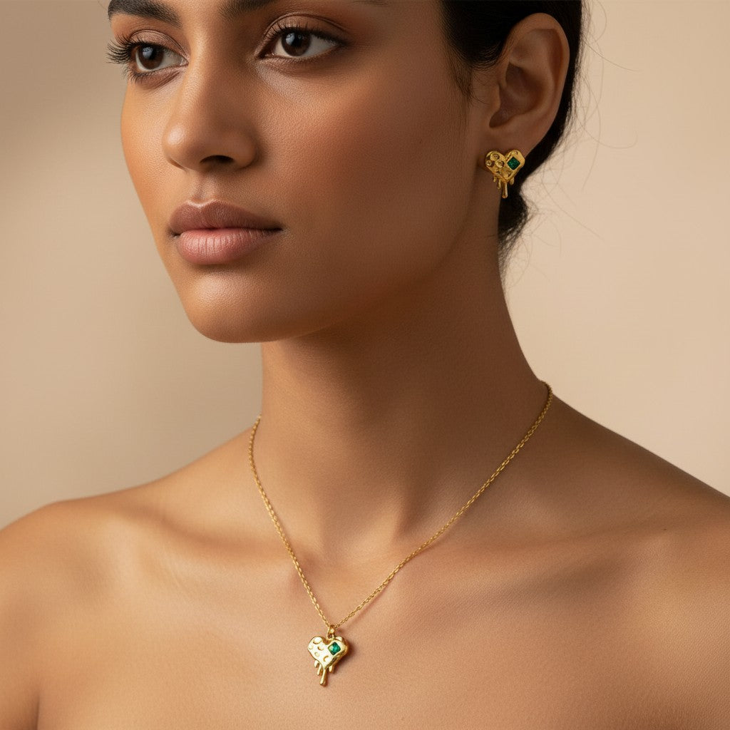 Woman wearing K-Glow Emerald Heart Drip Gold-Plated Anti-Tarnish Jewellery Set for Women - Melted Heart Necklace & Earrings against a beige background