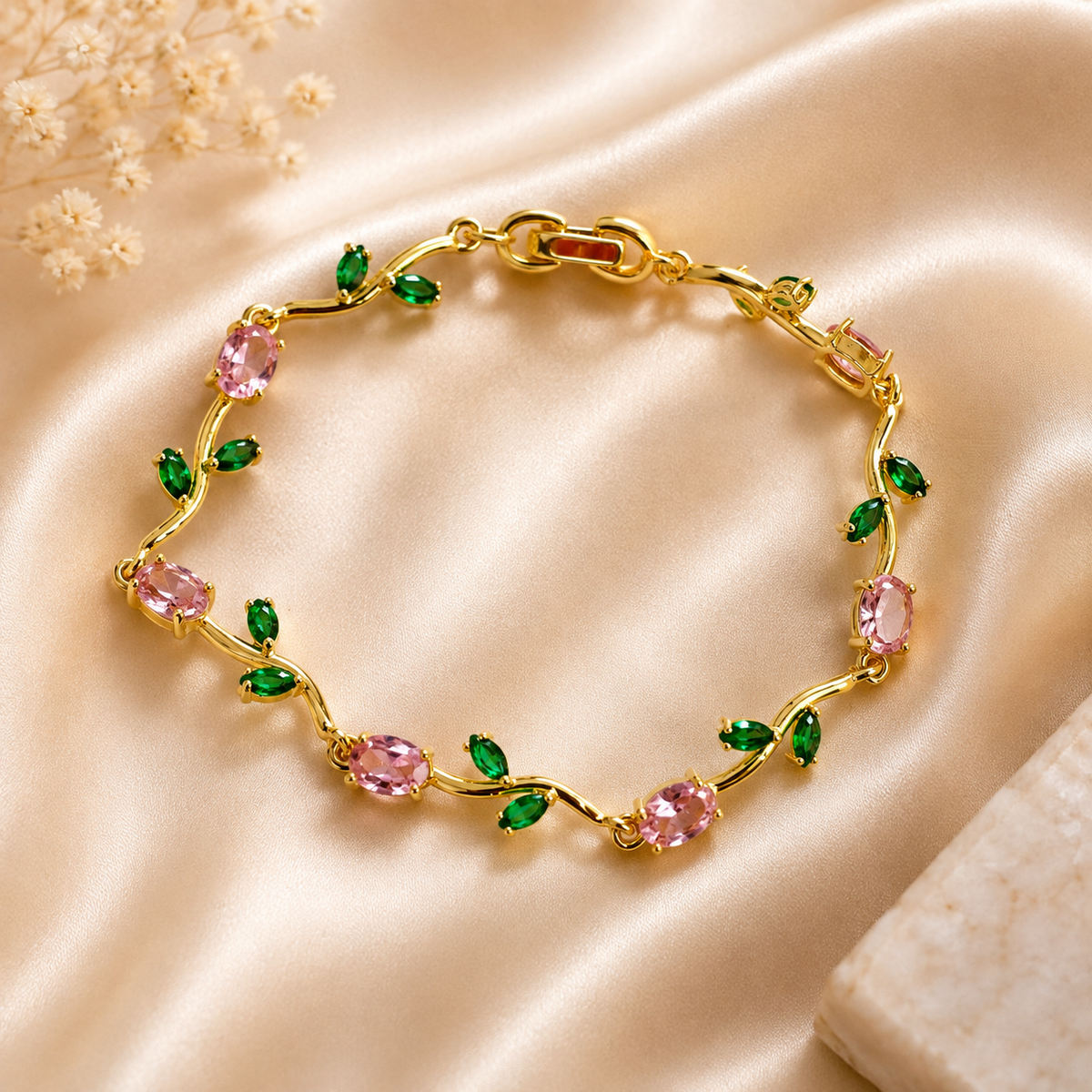 gold-plated anti tarnish tulip bracelet with pink oval stones and green leaf accents, on a beige satin fabric background
