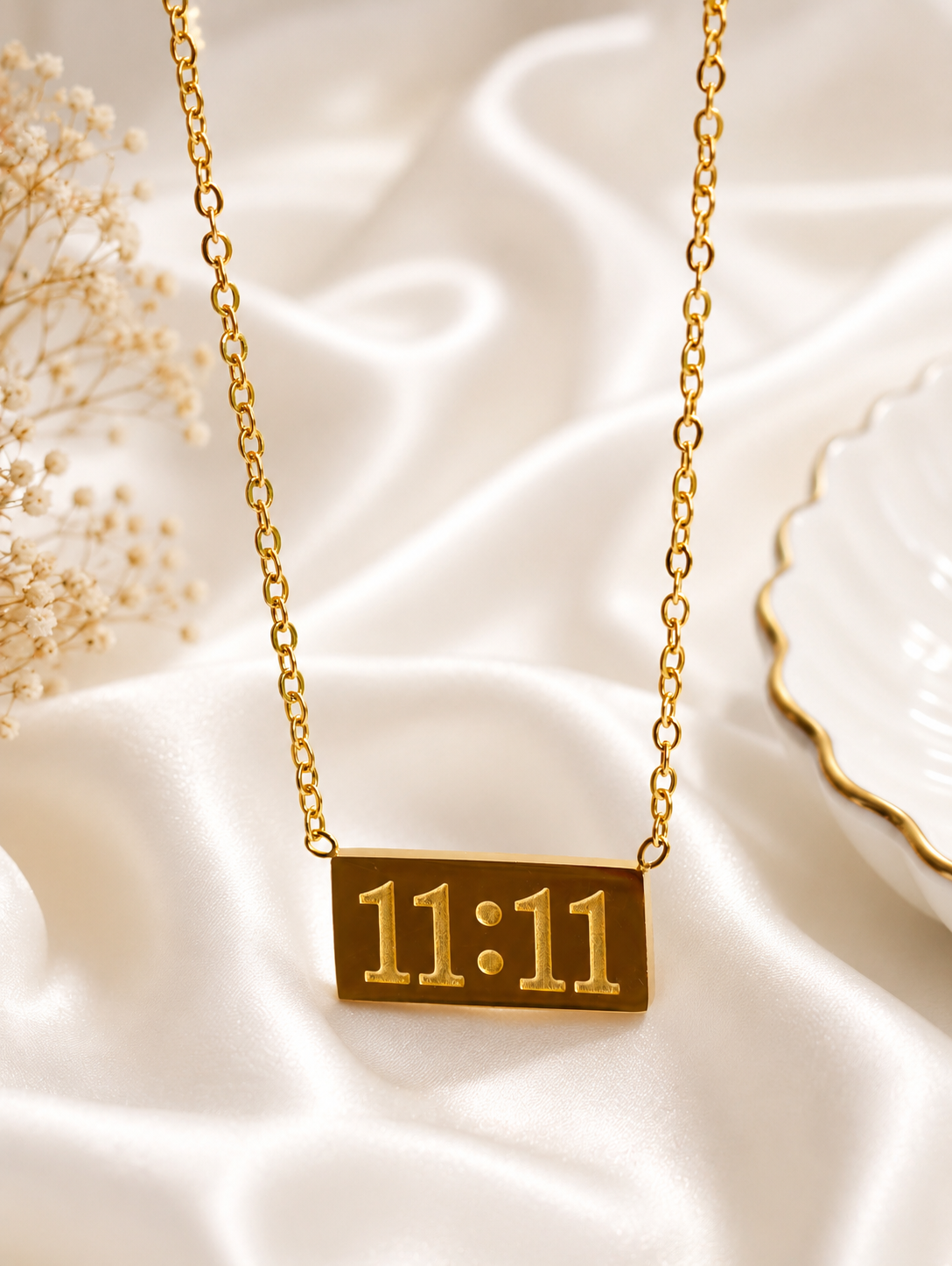 Serenity Gold Plated Anti Tarnish 11:11 Affirmation Necklace for Women over draped white satin fabric with dried flowers and a white plate in the background.
