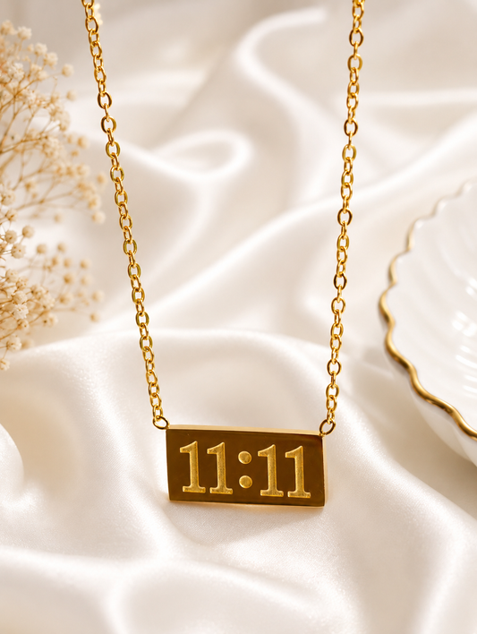 Serenity Gold Plated Anti Tarnish 11:11 Affirmation Necklace for Women over draped white satin fabric with dried flowers and a white plate in the background.