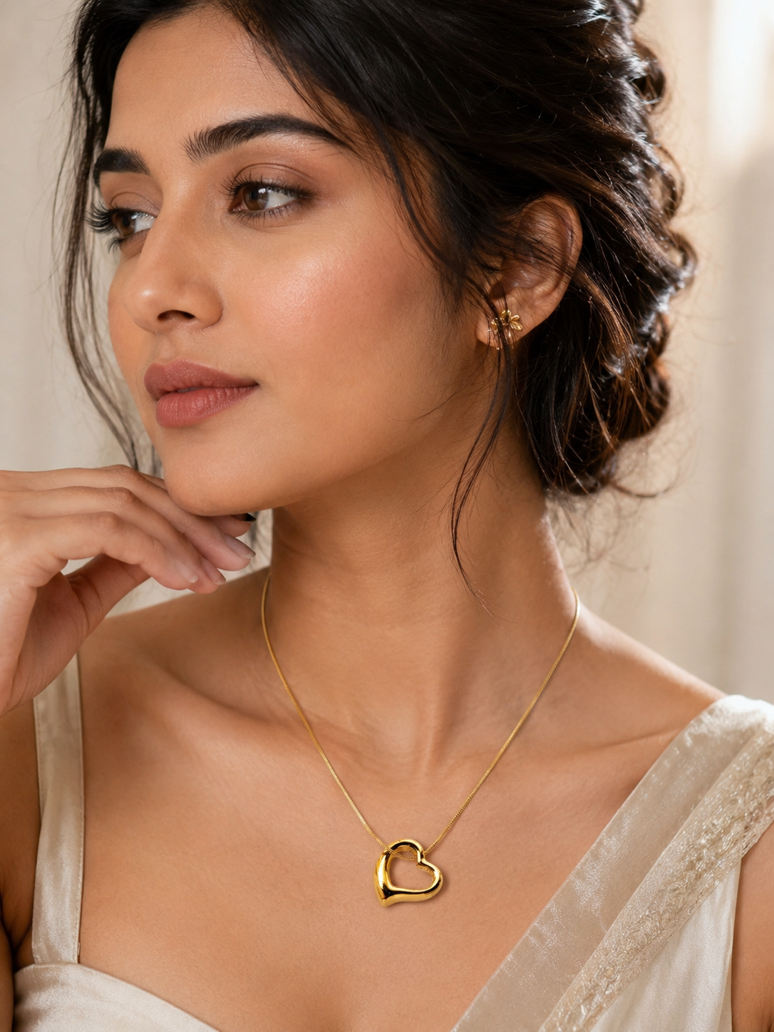A woman wearing Aurelia Gold Plated Anti Tarnish Tilted Heart Necklace against a soft neutral background.